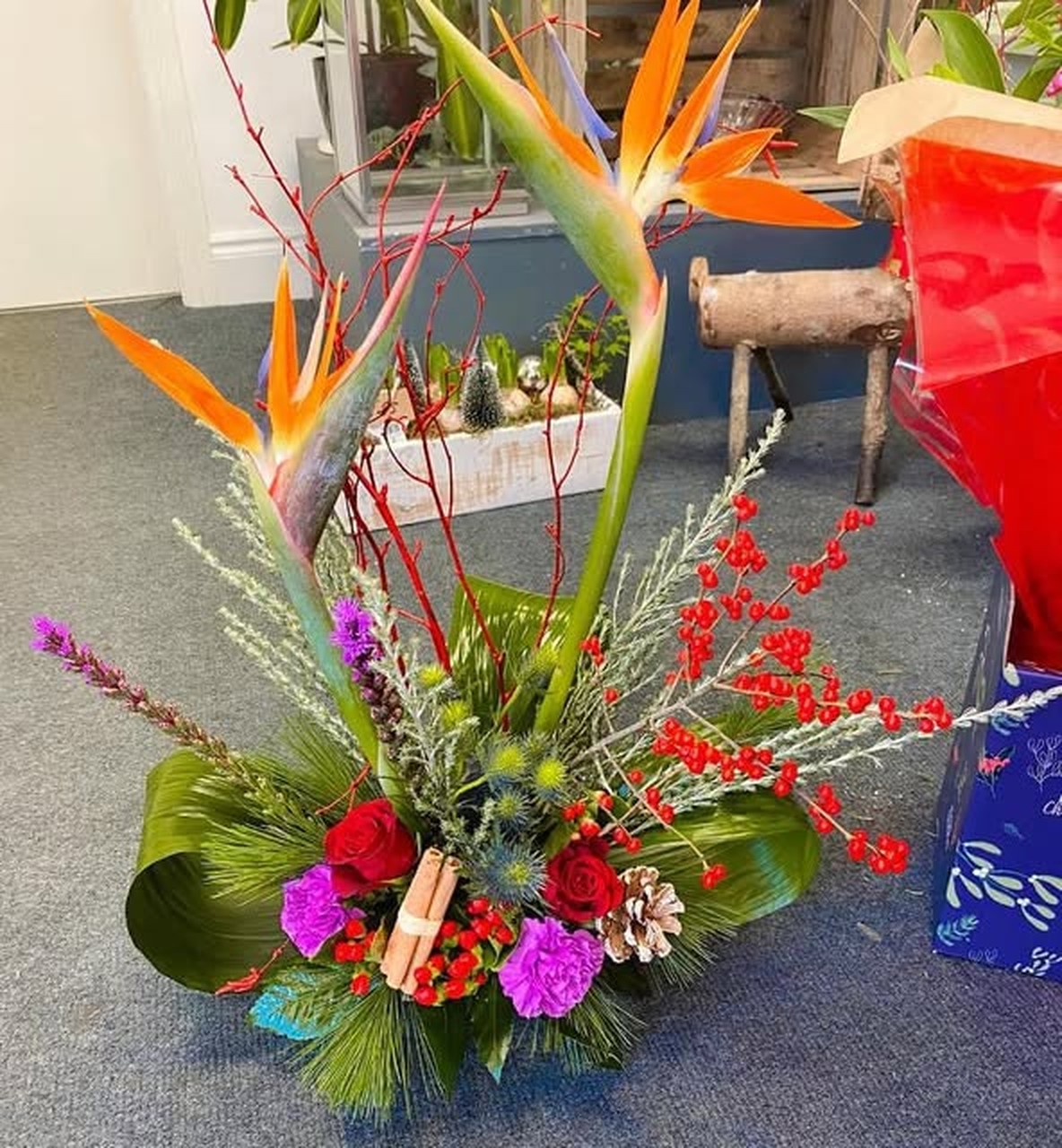 Seasonal arrangement from FloraBelle — birds of paradise, red roses and winter greenery inside the shop